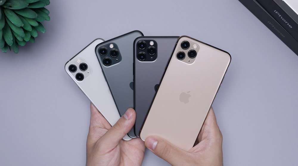 Hands holding four pre-owned iPhones